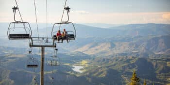 Two people riding up a ski lift in the summertime