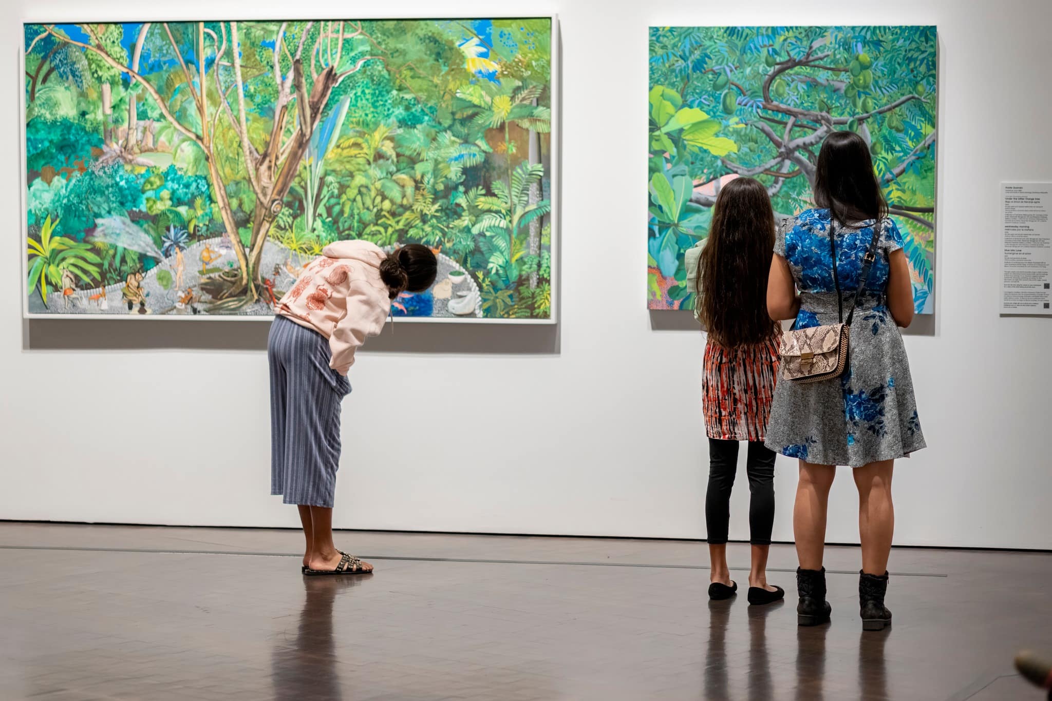 Three people standing in front of nature-inspired artwork at a museum