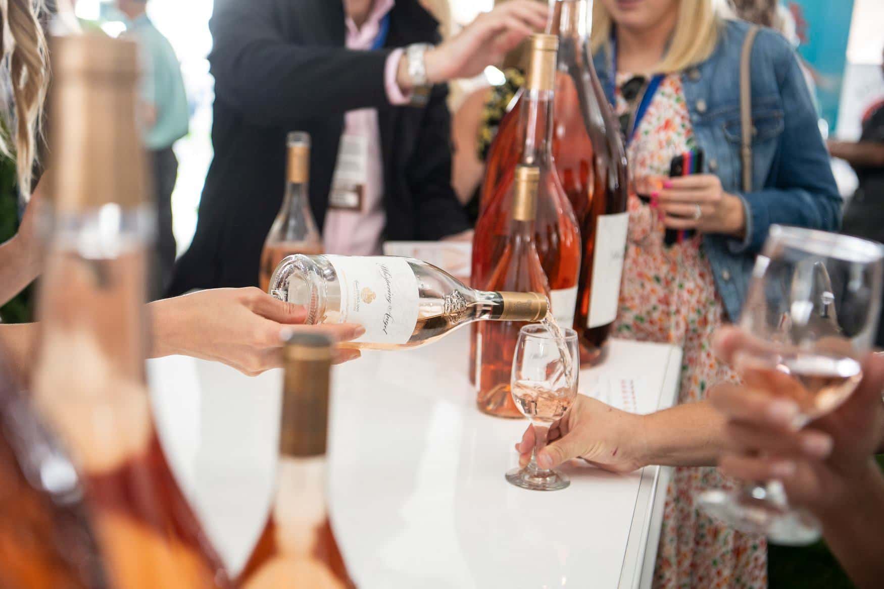 Wine representative pouring a rose into visitor's sampling glass at a fesitval