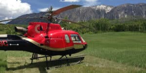 Red helicopter in field with mountains in the back
