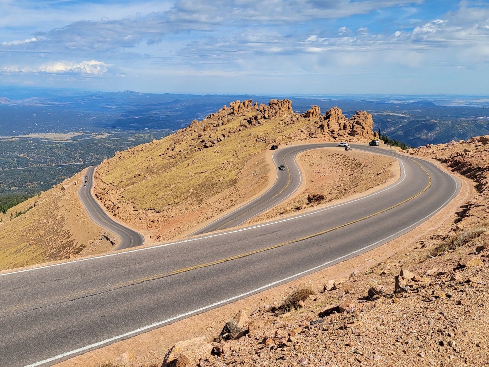 A few cars driving up Pikes Peak Highway with view of the switchbacks