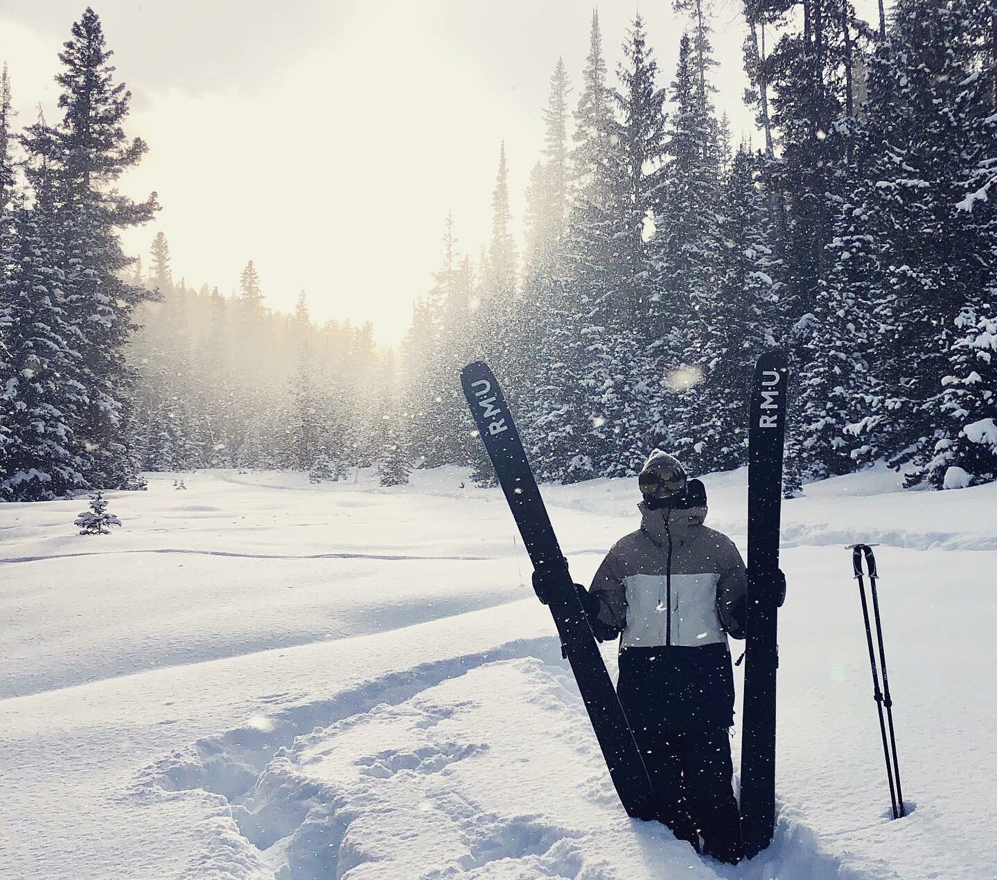 Skier in black jacket standing in deep powder snow in Breckenridge holding two black Rocky Mountain Underground skis